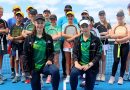Hobart juniors Zola and Escher Case-Boag, kneeling in front of the Tasmanian under 12s Bruce Cup team on a tennis court.