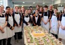 Montrose Bay High School students and teachers in aprons standing behind a table full of food.