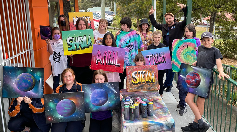 Crewative Arts Connect students show off their art work featuring their names and planets.